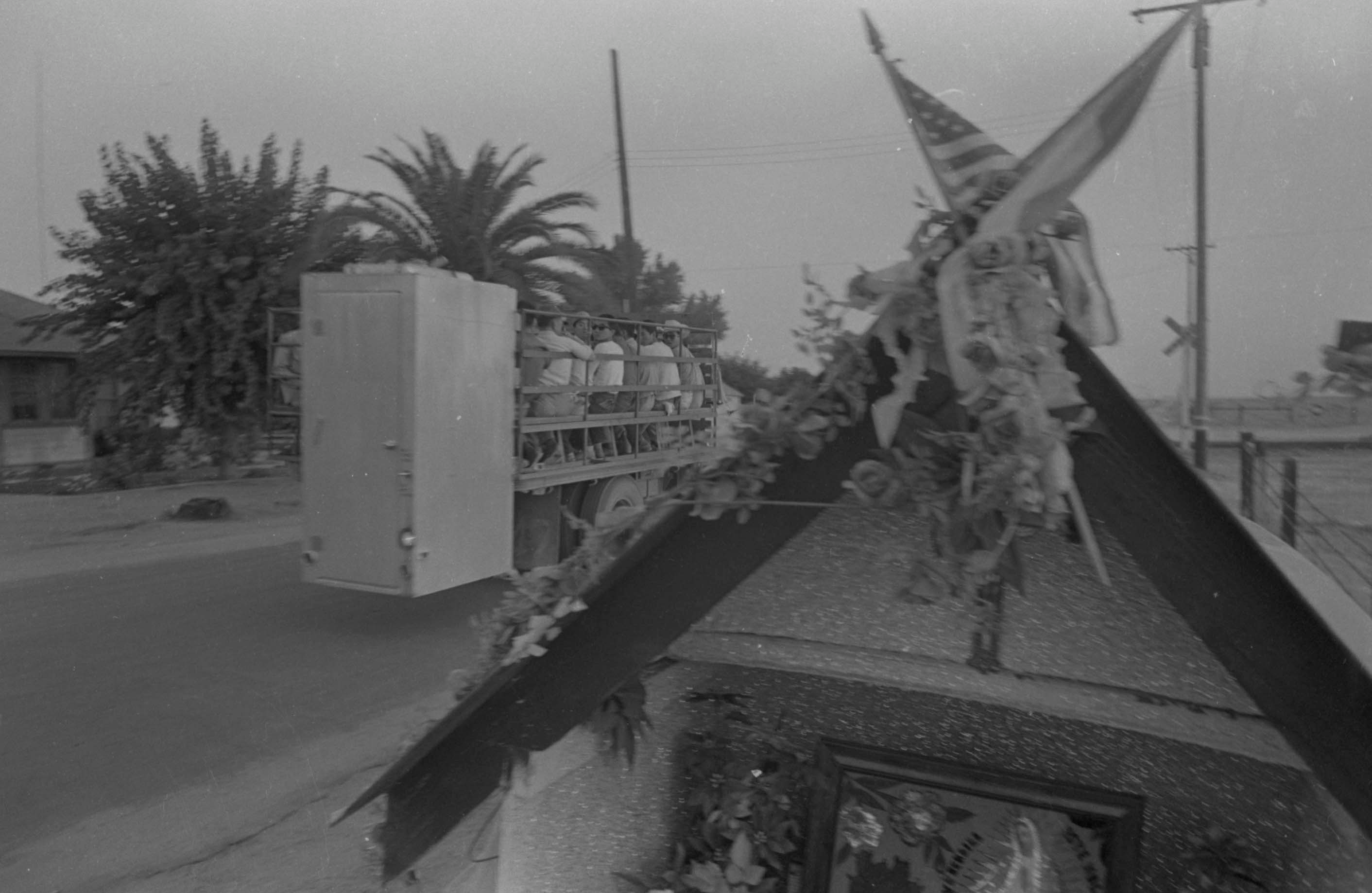 Truck with workers driving by altar chapel on station wagon, Delano, 1966