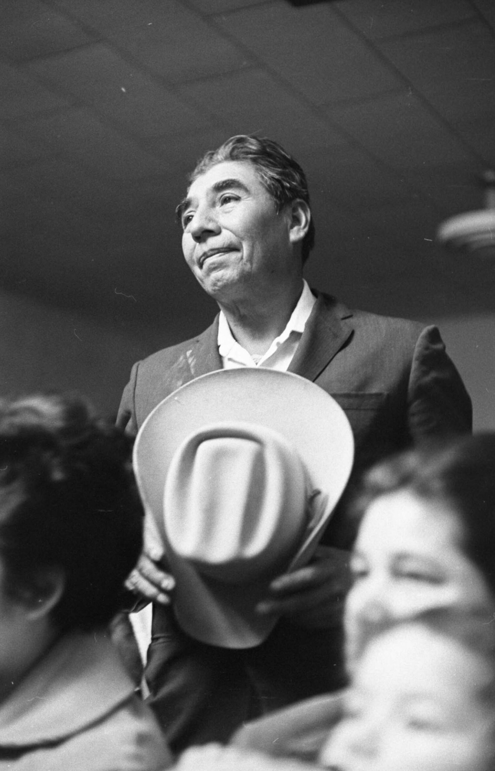 Felix Zapata thanks the Union for helping him repair his car during a Friday night meeting at Negrito Hall in Delano, California in 1966. Socorro Méndez and Asunción Zapata are visible in the foreground. Félix Zapata agradece a la Unión por ayudarlo a reparar su automóvil durante una reunión el viernes por la noche en Negrito Hall en Delano, California, en 1966. Socorro Méndez y Asunción Zapata son visibles en primer plano.