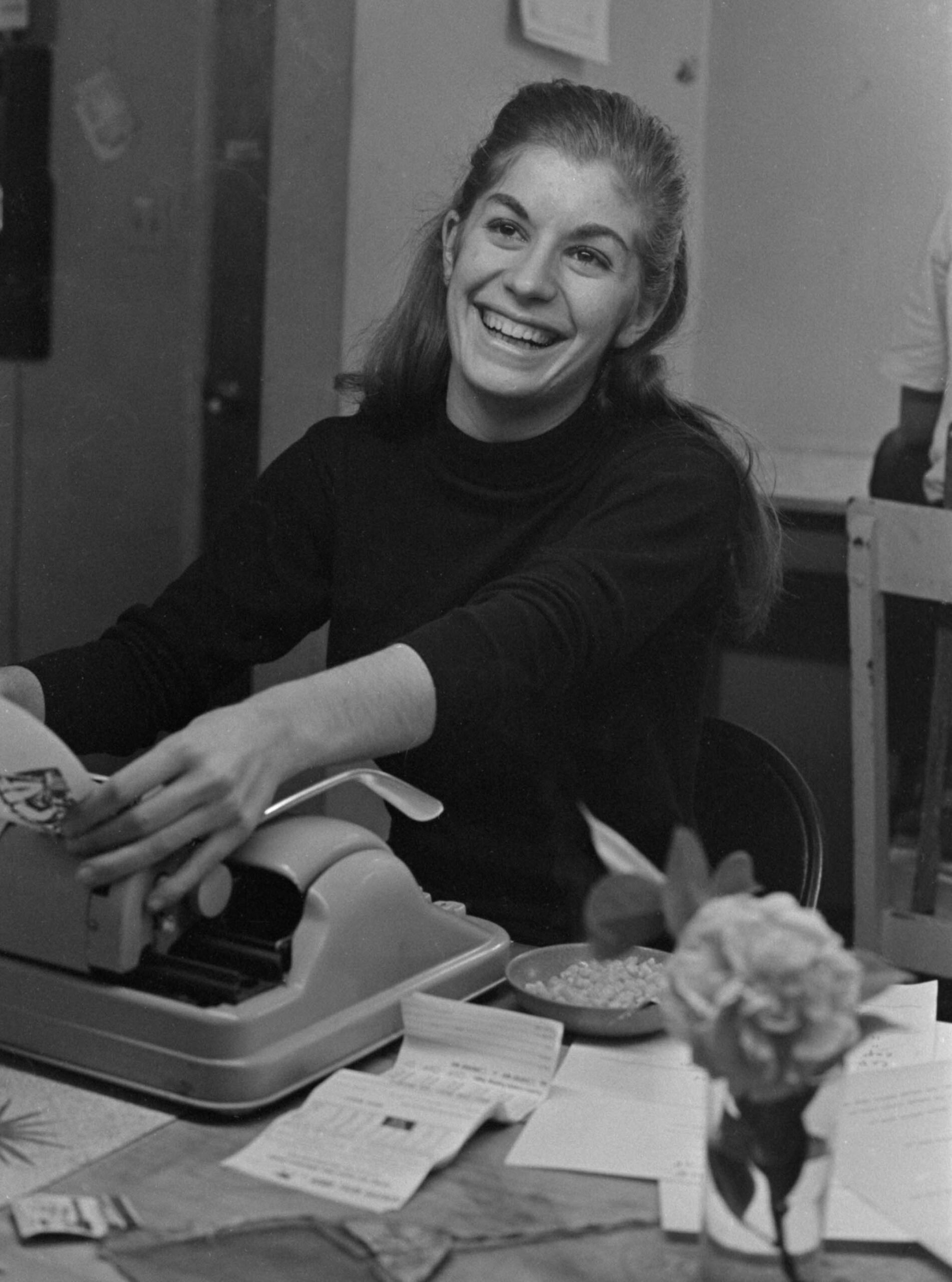 Donna Haber smiles as she removes a sheet of paper from a typewriter. She is working at El Malcriado's office in Delano. Donna Haber sonrie mientras quita una hoja de papel de la máquina de escruibir. Ella trabaja en la oficina de El Malcriado.