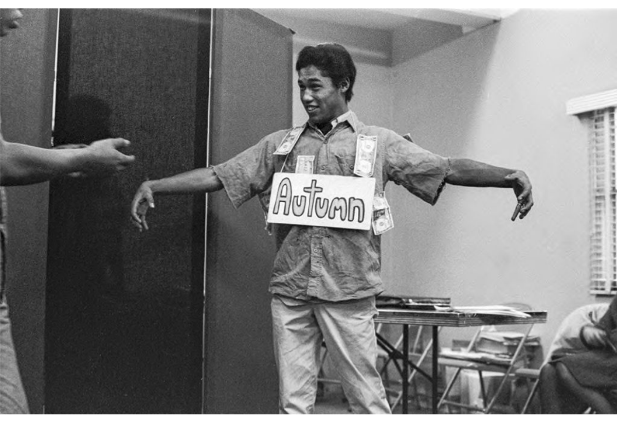 Daniel Valdez strikes a pose with a sign that reads "Autumn" on his chest and dollar bills around his shirt.</p>
<p>Daniel Valdez posa con un cartel que dice "Otoño" en su pecho y billetes de un dólar alrededor de su camisa.