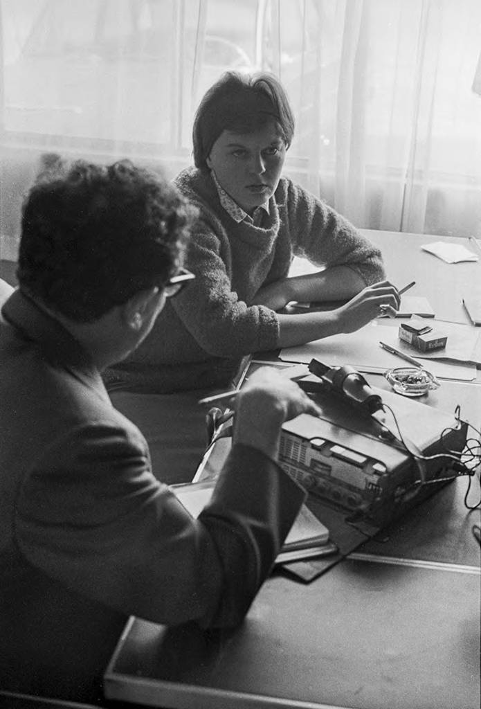 West coast editor of People's World Sam Kushner is interviewing Bonnie Chatfield. Chatfield is sitting at at the NFWA's Service Center office. El editor de la costa oeste de People's World, Sam Kushner, entrevista a Bonnie Chatfield. Chatfield está sentada en en la oficina del Centro de Servicio de NFWA.