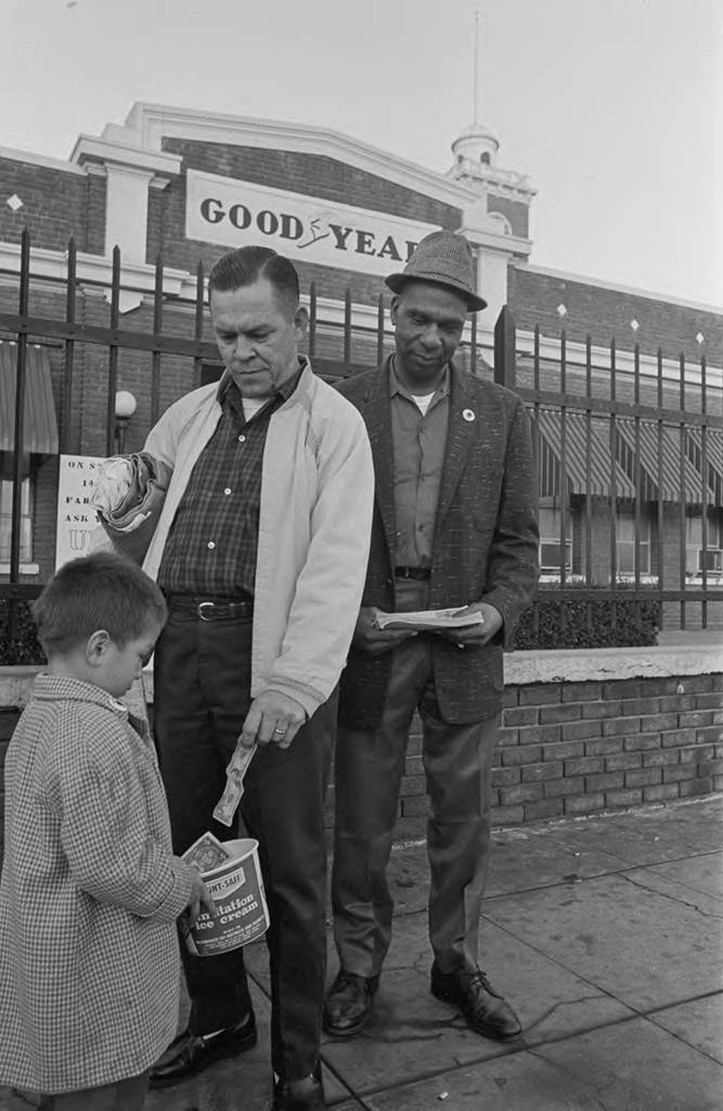 A child is collecting donations in front of the Goodyear Rubber Company, located at 6701 South Central Avenue. Los Angeles, California, November 1966. Photo by Emmon Clarke.